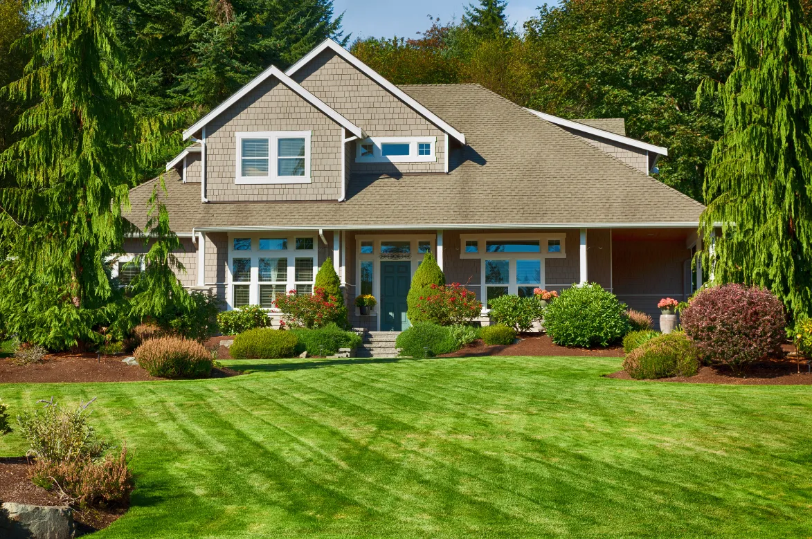 A picture of a house with beautiful green grass in front that has just been cut.